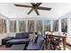 Inviting sunroom with a large sectional sofa, dining table, ceiling fan, and scenic views of the surrounding woods at 980 Pine Grove Pointe Dr, Roswell, GA 30075