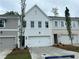 A new townhome featuring a white garage door and brick accents complemented by manicured landscaping at 105 Priestwood Ln, Acworth, GA 30102