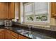 Kitchen features double sink, tile backsplash, wooden cabinets and a window letting in natural light at 173 Northshore Xing, Dallas, GA 30157