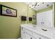 Bathroom featuring green walls, decorative artwork, and white cabinets at 3795 Duckcove Way, Cumming, GA 30041
