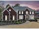 Elegant brick home featuring a symmetrical design, arched entryway, and manicured landscaping at 3795 Duckcove Way, Cumming, GA 30041