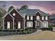 Charming brick home featuring symmetrical design elements and professionally landscaped front yard under a twilight sky at 3795 Duckcove Way, Cumming, GA 30041