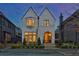 Charming two-story home with white brick, an arched entry, manicured landscaping, and a warm, inviting glow at dusk at 250 4Th St, Fayetteville, GA 30214