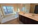 Bright bathroom featuring a soaking tub with a large window and a double sink vanity with dark wood cabinets at 4440 Cedar Bridge Walk, Suwanee, GA 30024