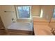 Bright bathroom featuring a soaking tub with a large window and a vanity with a white countertop at 4440 Cedar Bridge Walk, Suwanee, GA 30024