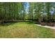 Landscaped backyard with stone fireplace and outdoor seating offers an inviting retreat in a woodsy setting at 404 Queensbury Pl, Acworth, GA 30102