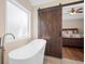 Bright bathroom features a modern soaking tub and sliding barn door to the main bedroom at 404 Queensbury Pl, Acworth, GA 30102