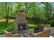 Outdoor fireplace with wicker seating surrounded by lush greenery, creating a relaxing space at 404 Queensbury Pl, Acworth, GA 30102