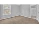 A carpeted bedroom with light gray walls and a view to the en-suite bathroom at 7176 Ravenwood Ln, Lithonia, GA 30038