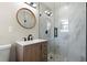Modern bathroom featuring a vanity, round mirror, and a tiled shower with glass doors at 3376 Irish Ln, Decatur, GA 30032