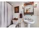Bathroom featuring a shower-tub combo, white wainscoting, pedestal sink, and a wood-framed mirror at 1109 Pine Grove Ne Ave, Brookhaven, GA 30319