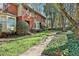 Charming red brick townhome featuring a bay window, walkway, and mature trees at 1384 Sheffield Glen Ne Way, Atlanta, GA 30329