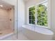 Bright bathroom with modern tub, tiled shower and large window with backyard view at 3364 Knollwood Nw Dr, Atlanta, GA 30305