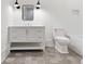 Bright bathroom with a white vanity, drawers, modern lighting, gray tiled floors, and a white toilet and tub at 3364 Knollwood Nw Dr, Atlanta, GA 30305