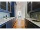 Hallway showcasing a butler's pantry with navy cabinets and marble countertops on either side at 3364 Knollwood Nw Dr, Atlanta, GA 30305