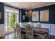 Elegant dining room with wainscoting, blue walls, and an ornate chandelier over a wooden table at 7492 Shadburn Ferry Rd, Cumming, GA 30041