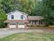 Charming split-level home featuring a two-car garage and partially bricked exterior with lots of mature trees at 235 Shallowford Nw Rd, Kennesaw, GA 30144