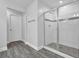 Tiled shower with a glass door, complemented by gray wood-look flooring in the bathroom at 3945 Hamilton Cove Ct, Cumming, GA 30028