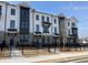 Exterior view of townhomes with brick and white siding, dark accents, and black fencing in front of the property at 627 Silva St # 127, Cumming, GA 30040
