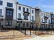 New townhome exterior featuring a brick and white facade with dark accents and black fencing in front at 627 Silva St # 127, Cumming, GA 30040