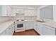 This kitchen boasts white cabinets, countertops, and appliances, paired with hardwood floors and a stainless steel sink at 2209 N Forest Trl, Dunwoody, GA 30338