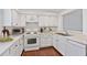 This kitchen features white cabinets, appliances, and countertops with hardwood floors and a stainless steel sink at 2209 N Forest Trl, Dunwoody, GA 30338