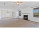 Spacious living room featuring carpet, a fireplace, a ceiling fan, and natural light from the surrounding windows at 2209 N Forest Trl, Dunwoody, GA 30338
