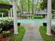 A community swimming pool area with light teal water, surrounded by lush landscaping and white columns at 2209 N Forest Trl, Dunwoody, GA 30338