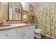 Well-lit bathroom with white cabinets, decorative wallpaper, and a shower curtain featuring a floral design at 91 Griggs Sw St, Marietta, GA 30064