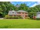 View of a red brick two-story home with black shutters, surrounded by lush green lawn and trees at 1135 Parkview Sw Way, Lilburn, GA 30047
