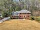 Two-story brick home featuring a well-manicured lawn and gray roof nestled within a wooded landscape at 1135 Parkview Sw Way, Lilburn, GA 30047