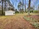 Large backyard featuring a detached garage with a white exterior and mature trees at 1336 Candlelite Ln, Snellville, GA 30078