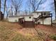 Back of house with wooden deck, stairs, and serene backyard with mature trees at 1336 Candlelite Ln, Snellville, GA 30078