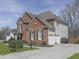 Side view of a beautiful brick and vinyl two-story home with an attached two car garage, manicured bushes, and a concrete driveway at 3891 Greensward Nw Vw, Kennesaw, GA 30144