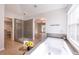 Spacious bathroom with a soaking tub, glass-enclosed shower, wood-look floors, and natural light at 10715 Glenbarr Dr, Johns Creek, GA 30097