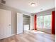 Bedroom featuring hardwood floors, closet with shelving, and a large window with bright red curtains at 10715 Glenbarr Dr, Johns Creek, GA 30097