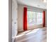 Bright bedroom featuring hardwood floors, a large window, and vibrant red curtains at 10715 Glenbarr Dr, Johns Creek, GA 30097