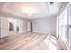Bright main bedroom with wood-look floors, large windows, a tray ceiling, and multiple doors at 10715 Glenbarr Dr, Johns Creek, GA 30097