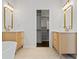 Bright bathroom featuring double vanities with sleek modern cabinets, lighting, and mirrors, plus a walk-in closet entrance at 2130 Waters Ferry Dr, Lawrenceville, GA 30043