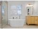 Bright bathroom featuring a modern soaking tub, sleek vanity, and gold accents, complemented by natural light from the window at 2130 Waters Ferry Dr, Lawrenceville, GA 30043