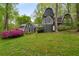 Spacious backyard featuring lush greenery, a charming facade with arched windows, and blooming azaleas at 2977 Glover Dr, Cumming, GA 30040