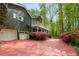Paver driveway leading to a charming two-story home with white garage doors and mature trees at 2977 Glover Dr, Cumming, GA 30040