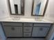 Double vanity bathroom with gray cabinets, white countertops, and two framed mirrors with vanity lighting at 623 Silva St # 130, Cumming, GA 30040