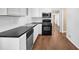 This kitchen features sleek black countertops, bright white cabinetry, stainless steel appliances and hardwood flooring at 4222 Webb Rd, Tucker, GA 30084