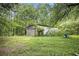 Exterior shot of storage shed with large doors, nestled in a lush green backyard with surrounding trees at 8600 Andy Mountain Ct, Villa Rica, GA 30180