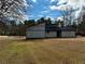Side angle view of a grey home with a spacious yard, showcasing natural light and a modern design at 1902 Mack Rd, Douglasville, GA 30135