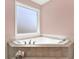 Large corner soaking tub with tile surround and frosted window at 114 Hardwood Ln, Canton, GA 30115