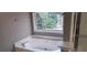 Corner bathtub next to the window that brings in natural light at 5763 Dexters Mill Pl, Buford, GA 30518