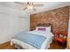 Cozy bedroom with exposed brick wall, hardwood floors, and a comfortable bed with blue throw at 1078 Piedmont Ne Ave # 203, Atlanta, GA 30309