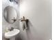 Charming powder room with a pedestal sink, round mirror, and gray brick accent wall at 125 Whitman Grv, Fayetteville, GA 30215